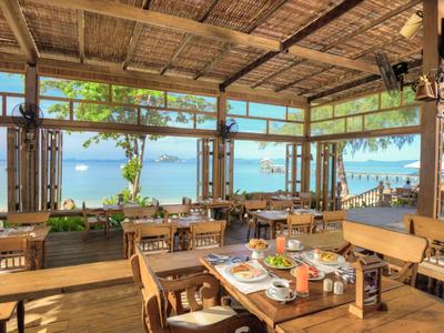 Ristorante aperto con mobili in legno e vista sul mare alla luce del giorno