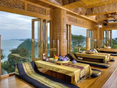 Luksusowe drewniane wnętrze z leżakami w otwartej przestrzeni z widokiem na morze i góry.