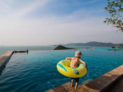Bambino con ciambella in piscina a sfioro con vista sul mare e sulle isole