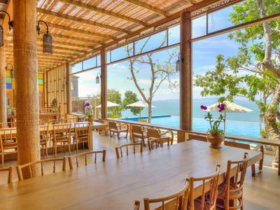 Sala da pranzo aperta con mobili in legno e vista mare in una giornata di sole