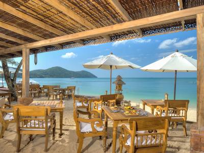 Ristorante all'aperto con mobili in legno, ombrelloni e vista sul mare e sulle montagne.