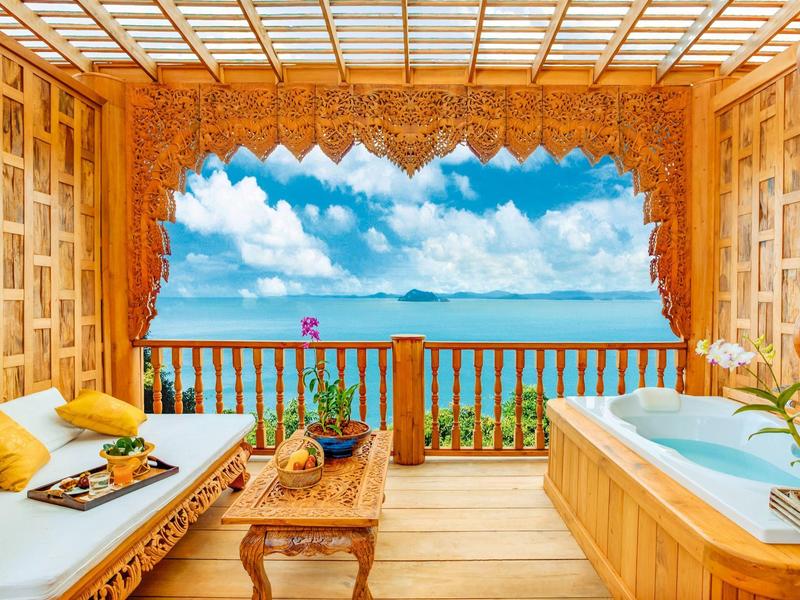 Terrazza in legno con vasca idromassaggio e vista sul mare sotto un cielo azzurro