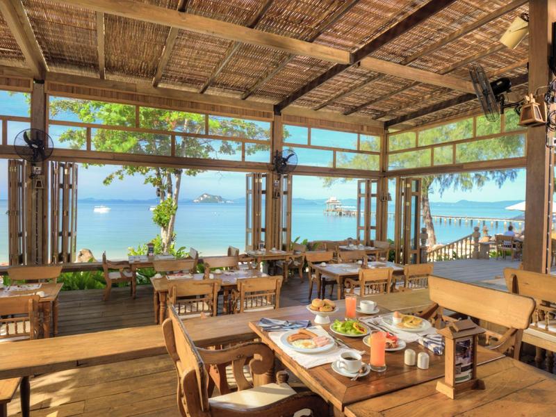 Ristorante aperto con mobili in legno e vista sul mare alla luce del giorno