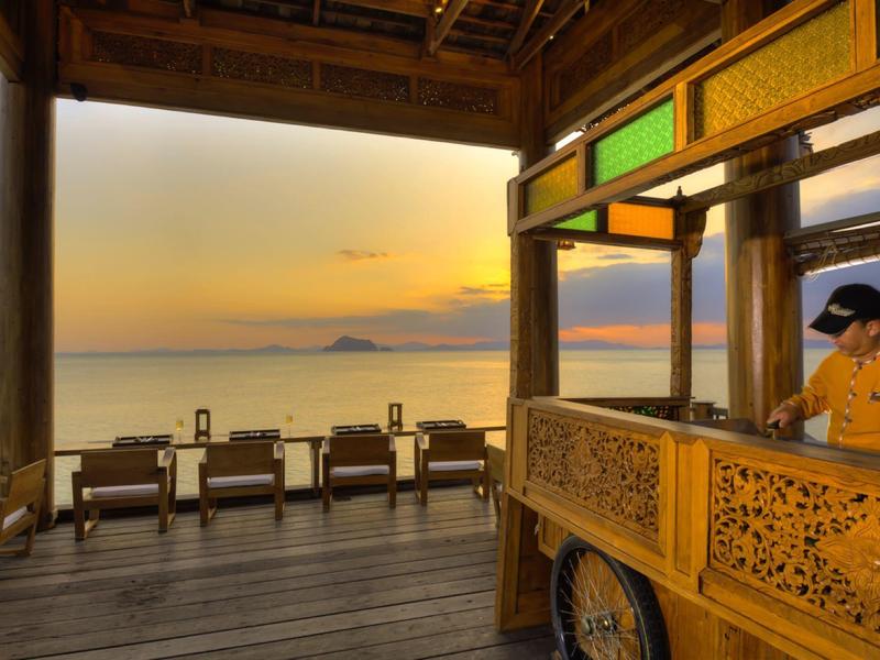 Una terrazza con posti a sedere e vista sul mare al tramonto in un hotel.