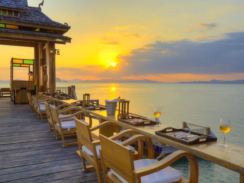 Molo di legno serale con sedie e tavoli sul mare al tramonto.