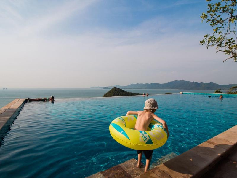 Bambino con ciambella in piscina a sfioro con vista sul mare e sulle isole