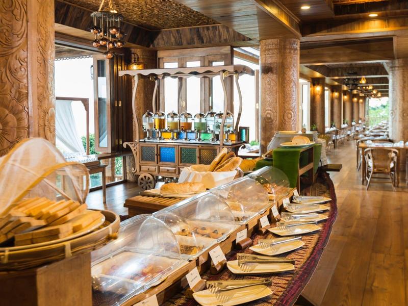 Area colazione elegante con buffet, colonne in legno e illuminazione moderna.