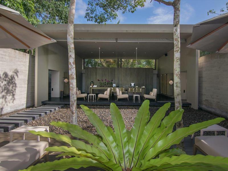 Moderner Außenbereich mit Sitzgelegenheiten unter einem überdachten Bereich und Pflanzen im Vordergrund