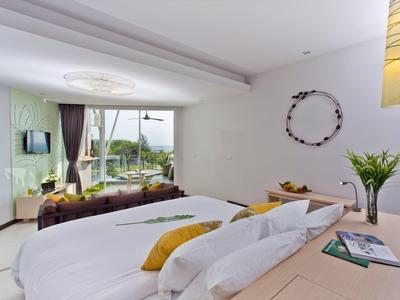 Chambre d'hôtel lumineuse avec lit double, coin salon et grande fenêtre avec vue sur la nature.