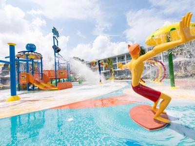 Parc aquatique avec aire de jeux d'eau, toboggans et figures colorées sous un jour ensoleillé.