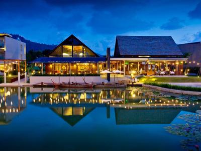Hôtel moderne la nuit avec façades éclairées et reflet dans l'eau.