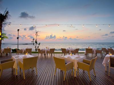Terrasse de restaurant avec des chaises jaunes au bord de la mer au coucher du soleil.