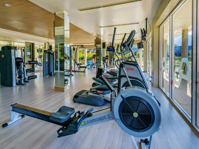 Palestra moderna con varie attrezzature e ampie finestre con vista sulle montagne.