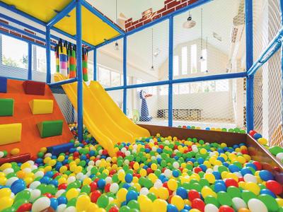 Aire de jeux intérieure colorée pour enfants avec toboggan et piscine à balles dans un espace moderne.