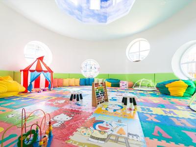 Salle de jeux lumineuse et colorée avec coussins au sol et jouets dans un hôtel.