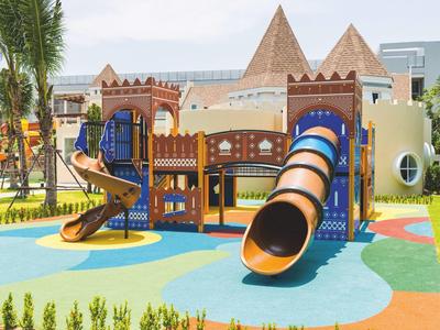 Terrain de jeux coloré avec toboggans et structures d'escalade sous un ciel bleu.