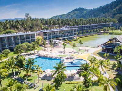 Grande resort con piscina, palme e montagne circostanti sotto il sole.