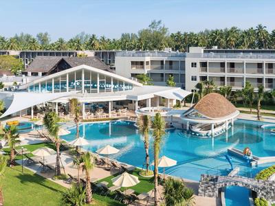 Resort di lusso con grande piscina, palme, sdraio e edifici moderni sullo sfondo.