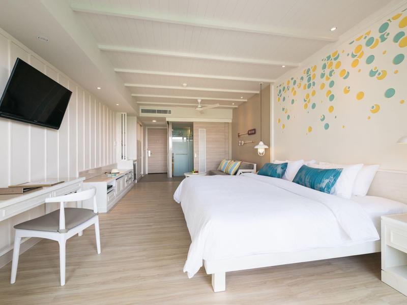 Chambre d'hôtel lumineuse avec deux lits, décoration murale et mobilier moderne.