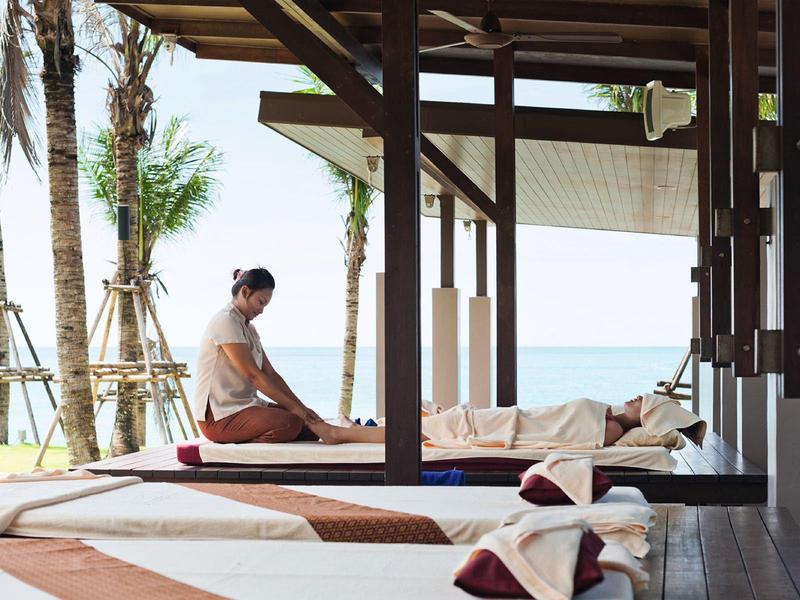 Des personnes se détendent sur des chaises longues sous un abri avec vue sur la plage.