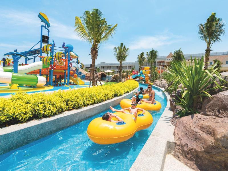 Famille sur un radeau dans la rivière paresseuse d'un parc aquatique de villégiature par une journée ensoleillée.