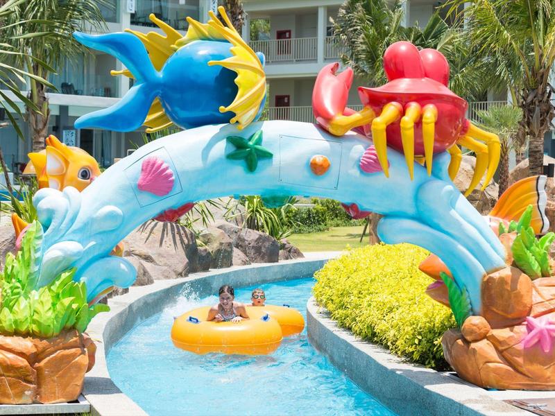 Toboggan aquatique coloré avec décorations marines et personnes dans la zone de la piscine du complexe