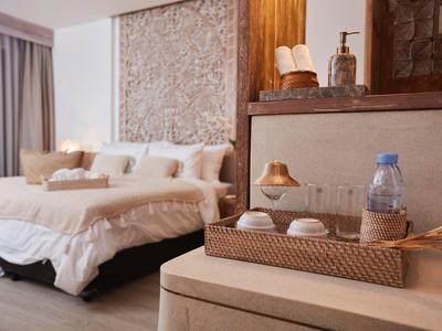 Modern eingerichtetes Schlafzimmer mit cremefarbener Dekoration, Korb und Wasserflasche auf dem Nachttisch.