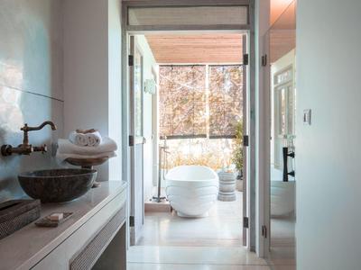 Moderner heller Badezimmerbereich mit freistehender Badewanne und großer Glasfront zum Außenbereich.
