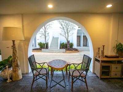 Gemütliche Sitzgruppe mit Metallstühlen und kleinem Tisch vor großem Fensterbogen mit Blick auf Hof.