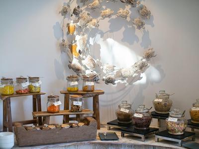 Buffet mit verschiedenen Gläsern voll Honig, dekoriert mit einem Blumenkranz an der Wand.