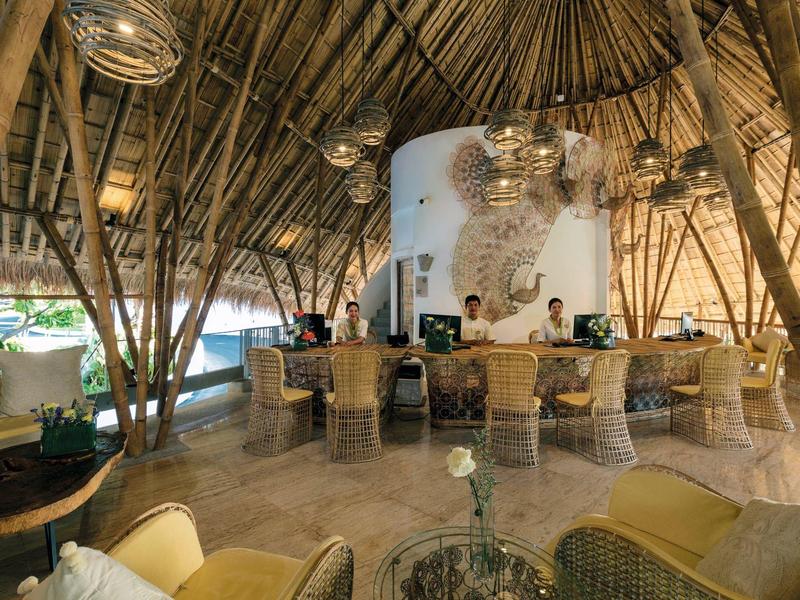 Otwarta recepcja hotelowa pod dachem bambusowym z nowoczesnym, inspirowanym naturą designem.