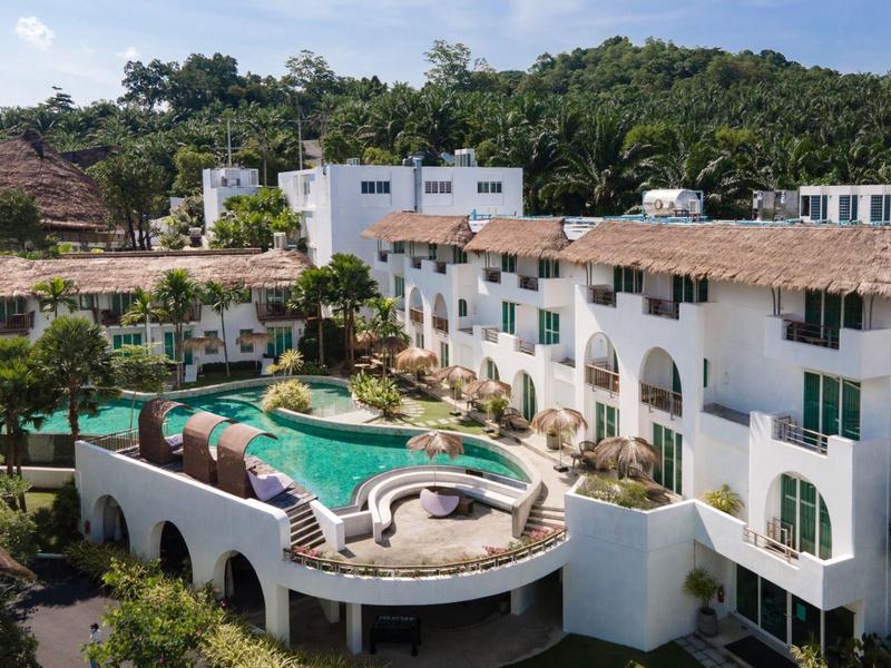 Hotel z okrągłym basenem na dachu w tropikalnym otoczeniu zielonych drzew.