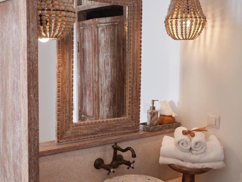 Nowoczesna łazienka z okrągłą umywalką, dużym lustrem i plecionymi lampami wiszącymi.