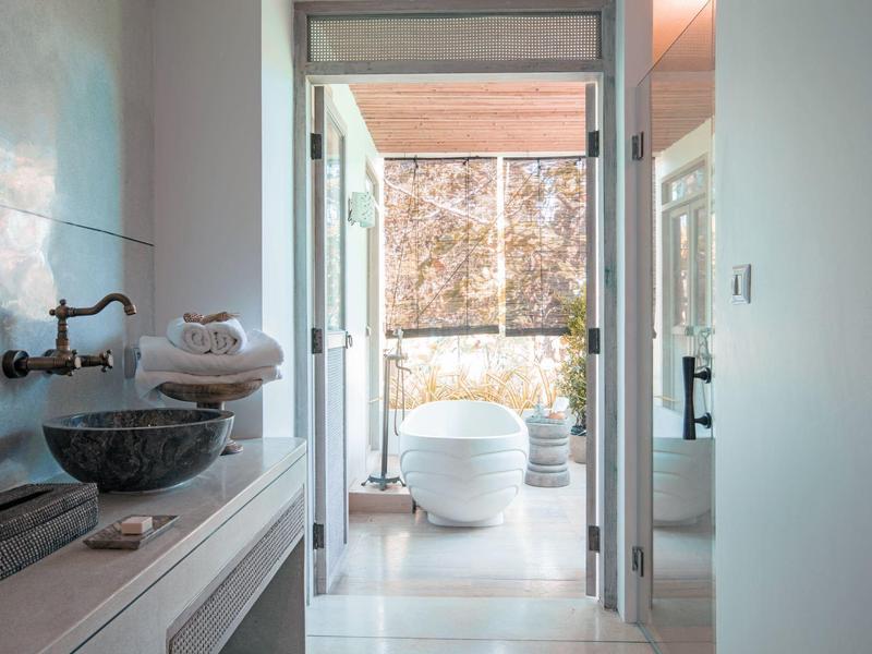 Widok przez drzwi na nowoczesną łazienkę z wolnostojącą wanną i umywalką.