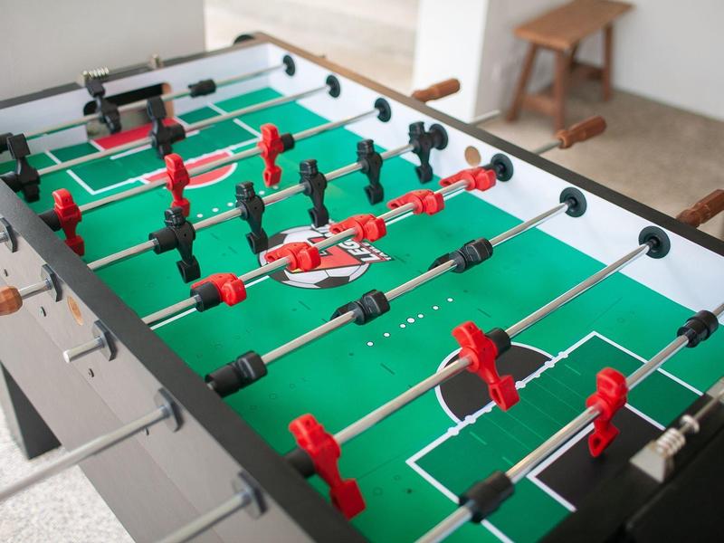 Stół do piłkarzyków z czerwonymi i czarnymi zawodnikami w jasnym wnętrzu.