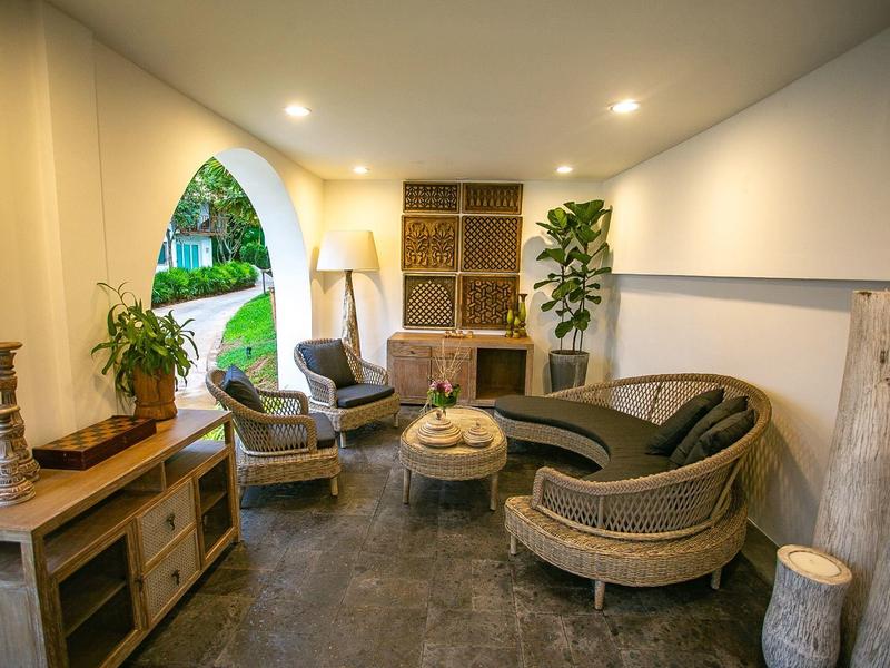 Przytulny salon z meblami z rattanu i roślinami, oświetlony przez łukowate otwarcie.