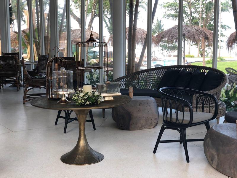 Przytulny salon z czarnymi meblami i dużymi szklanymi oknami z widokiem na palmy.