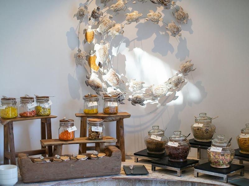 Różne przekąski i płatki w słoikach na drewnianych meblach z dekoracyjnym lustrem na ścianie w tle.