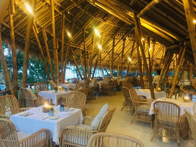 Przytulna otwarta restauracja z bambusowymi meblami i nastrojowym oświetleniem.