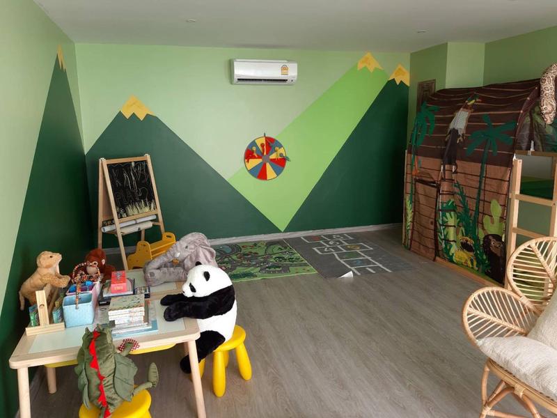 Pokój zabaw dla dzieci z drewnianym motywem farmy, edukacyjnym wzorem ściennym i różnymi zabawkami.