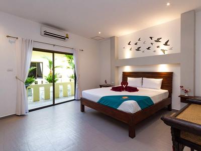 Hell eingerichtetes Schlafzimmer mit Doppelbett, Wanddeko, Klimaanlage und Zugang zum Balkon.