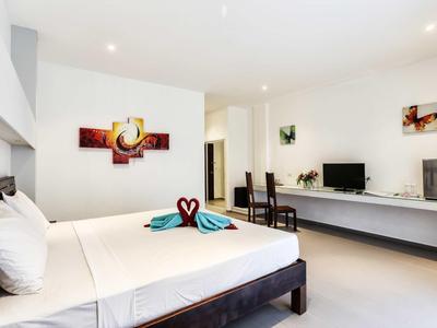 Modernes Schlafzimmer mit großem Bett, weißer Bettwäsche, dunklem Holz und minimalistischer Dekoration.