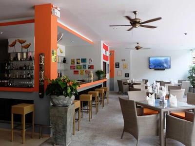 Moderner Gastraum mit Bar, Holzmöbeln, Deckenventilator und großem Fenster für Tageslicht.