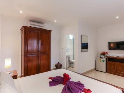 Schlichtes Schlafzimmer mit Holzschrank, Doppelbett, Klimaanlage, TV und angrenzendem Badezimmer.