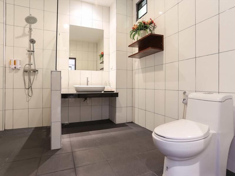 Modernes Badezimmer mit bodengleicher Dusche, weiß gekachelten Wänden und Toilette vorne rechts.
