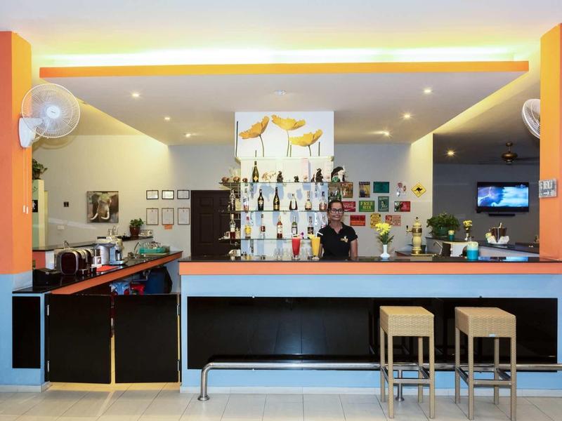 Hell belehnte Bar mit blauen Wänden, orangenen Säulen, hohen Hockern und dekorativen Flaschen.