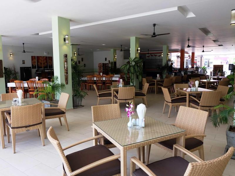 Großer heller Raum mit mehreren Holztischen und Stühlen, dekoriert mit Pflanzen und kleinen Blumenvasen.