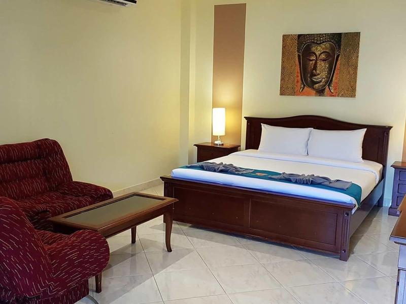 Ein Schlafzimmer mit Doppelbett, roten Sesseln, Nachttischlampen und einem Kunstwerk an der Wand.