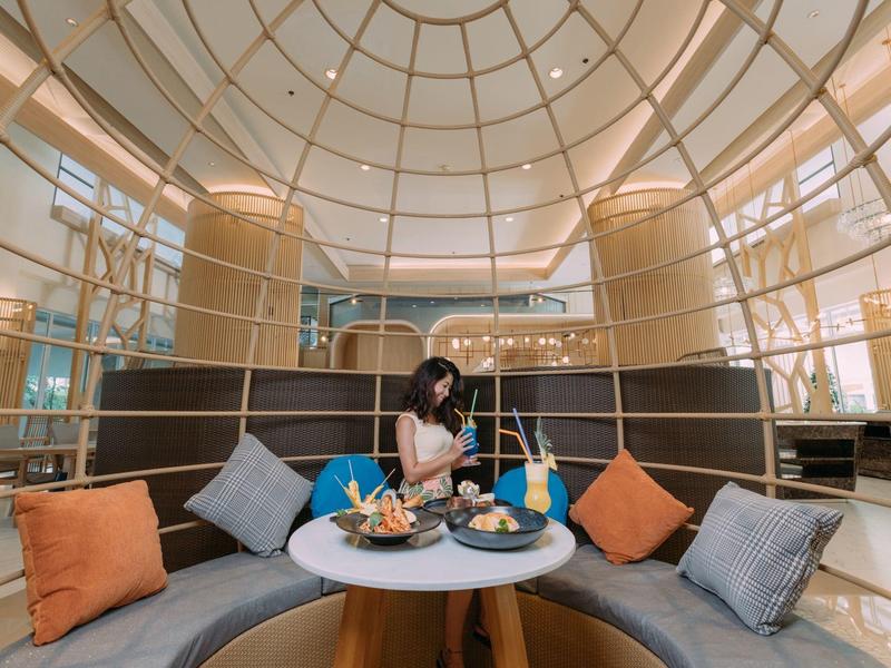 Area salotto elegante con divani rotondi, cuscini colorati e soffitto a cupola in un hotel