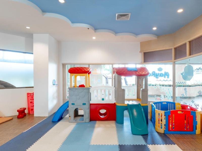 Stanza giochi luminosa per bambini con attrezzature colorate e ampie finestre.